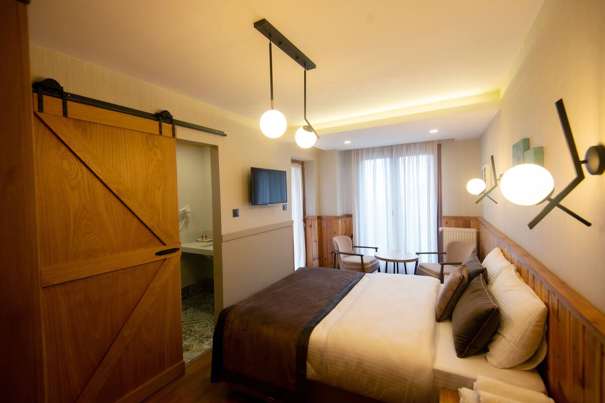 A hotel room with a bed, bedside tables, a desk, and a chair.