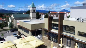 Un hotel llamado BIGESTE con un diseño moderno, una torre del reloj y vistas a montañas al fondo.