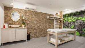 Un baño moderno con pared de piedra, un espejo redondo, un lavabo y una banca.
