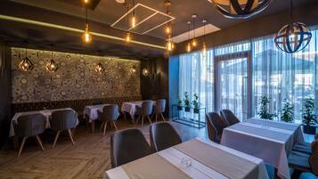 Un restaurante con paredes de diseño hexagonal, lámparas colgantes y vistas al exterior a través de amplios ventanales.