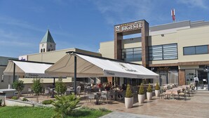 Un hotel con terraza al aire libre, una torre del reloj y un cartel que dice 'Hotel Bigeste'.