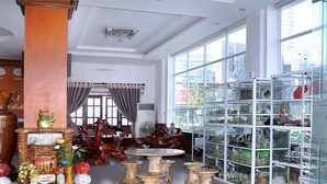 A spacious lobby with a large glass display case filled with decorative items, a wooden reception desk, and a chandelier. - A Dong Hotel (Da Nang)