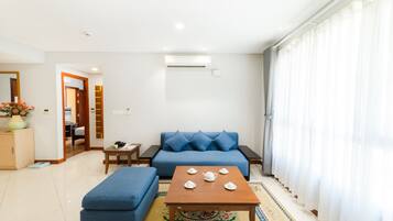 Una sala de estar moderna con un sofá azul, un reposapiés a juego, una mesa de centro de madera y una alfombra estampada.