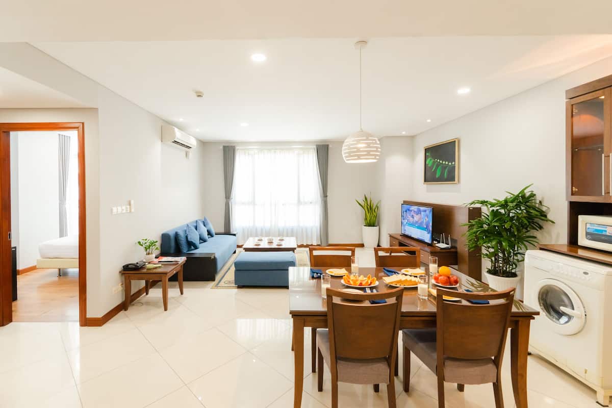 A modern living room with a dining area, a sofa, a TV, and a washing machine.