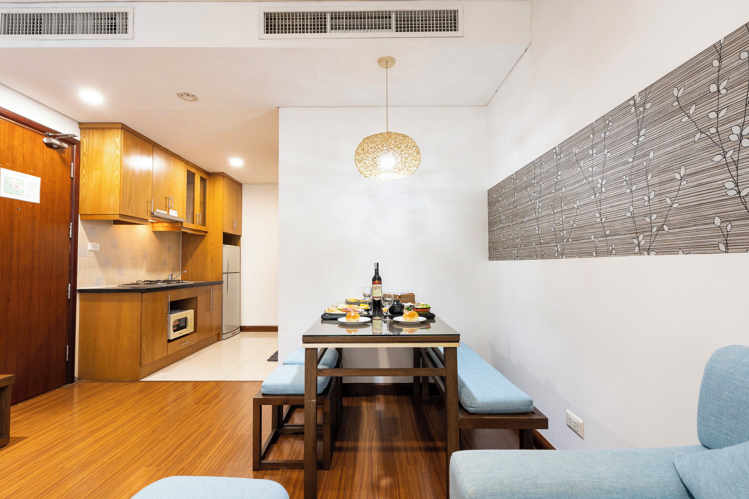 Una cocina moderna con armarios de madera, una mesa de comedor con cojines azules y un adorno de pared.