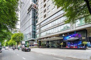 A multi-story building with a modern glass facade, a prominent entrance with a canopy, and signage indicating a hotel. - Lancaster Ho Chi Minh (Ho Chi Minh City)