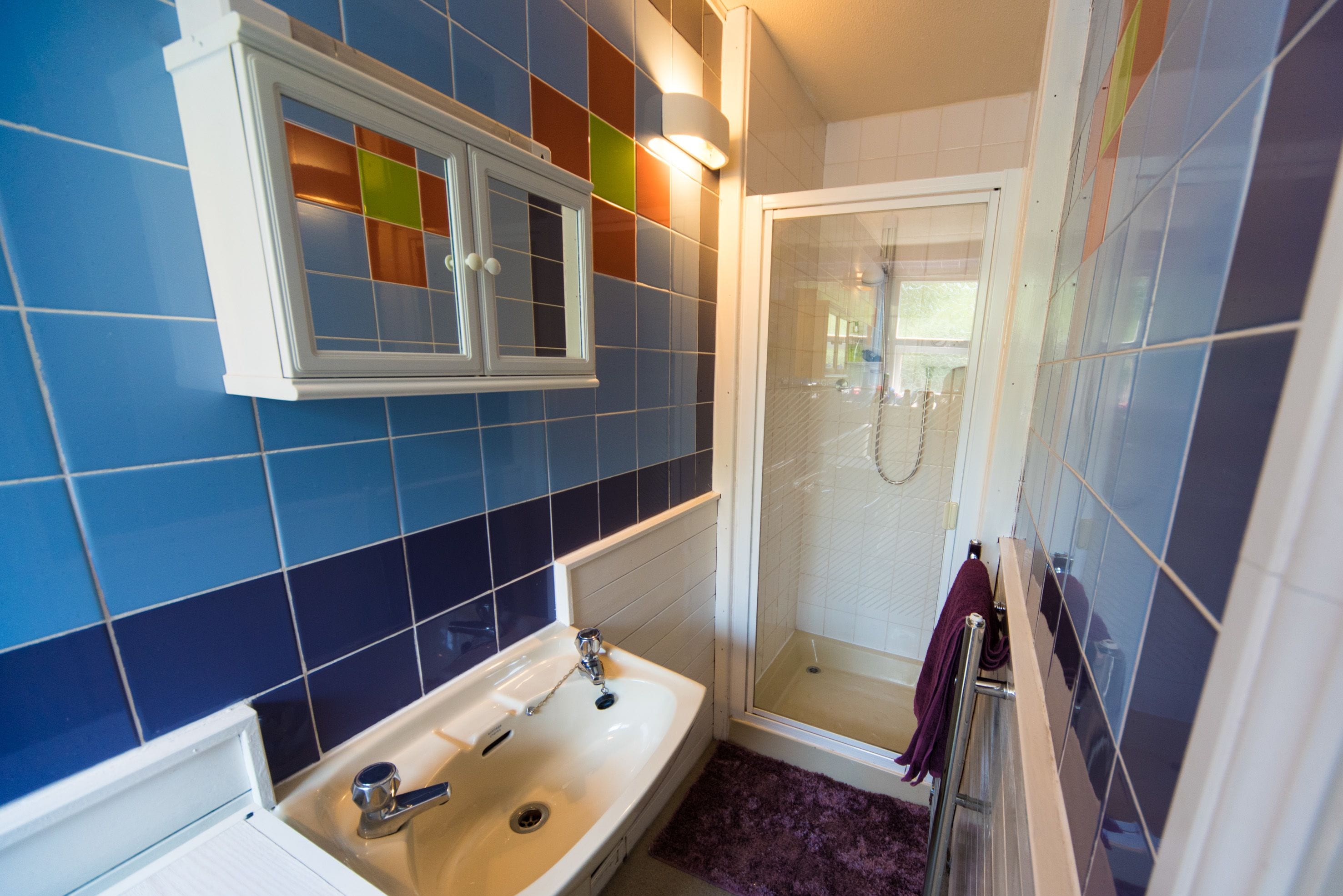 A bathroom with a white sink, a mirror, and a shower.