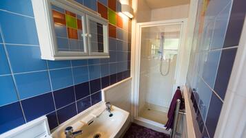 A bathroom with a white sink, a mirror, and a shower.