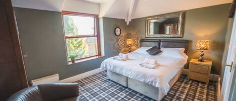A bedroom with a bed, a chair, a window, a mirror, and a lamp.