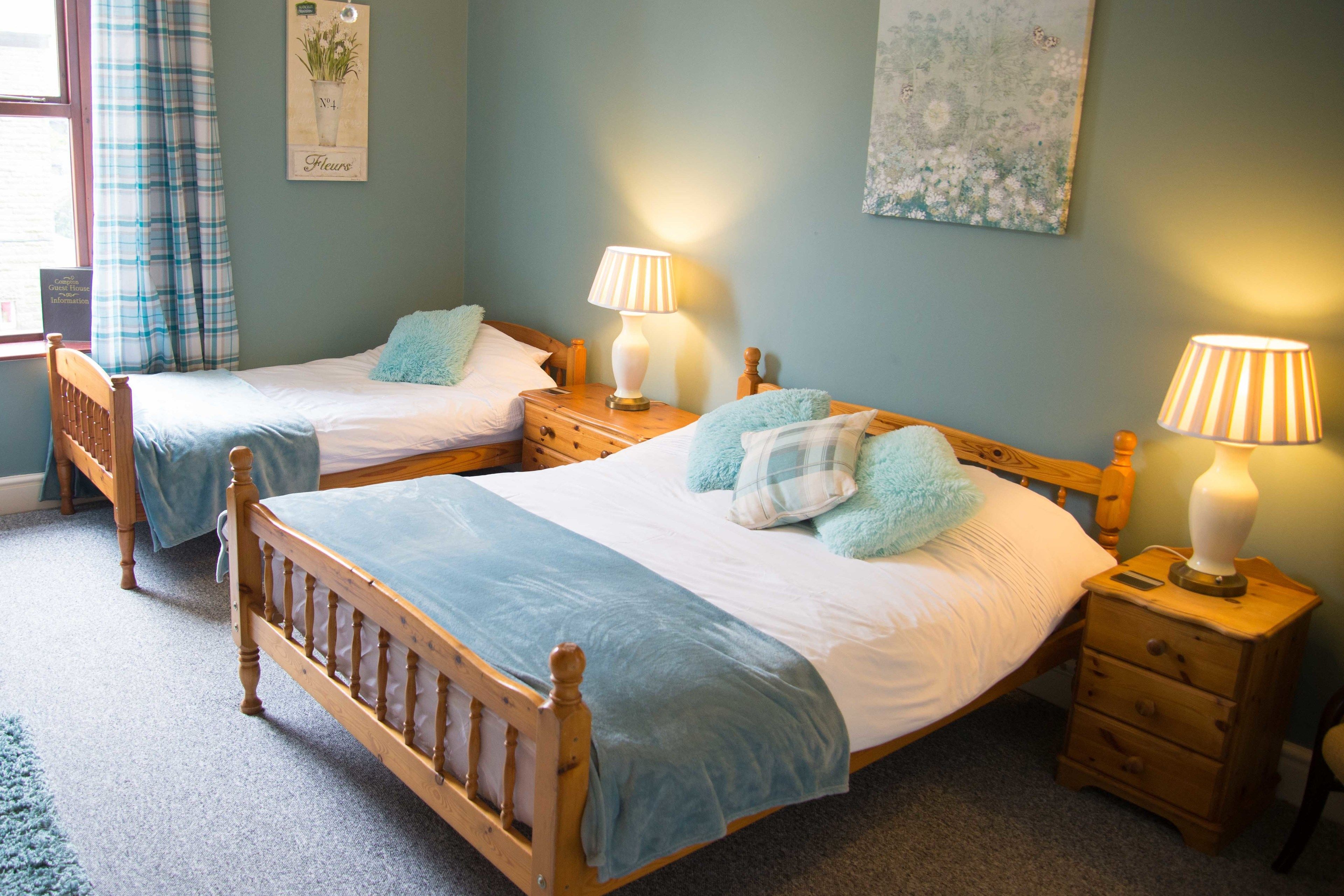 A bedroom with two wooden beds, each with a matching nightstand and lamp.