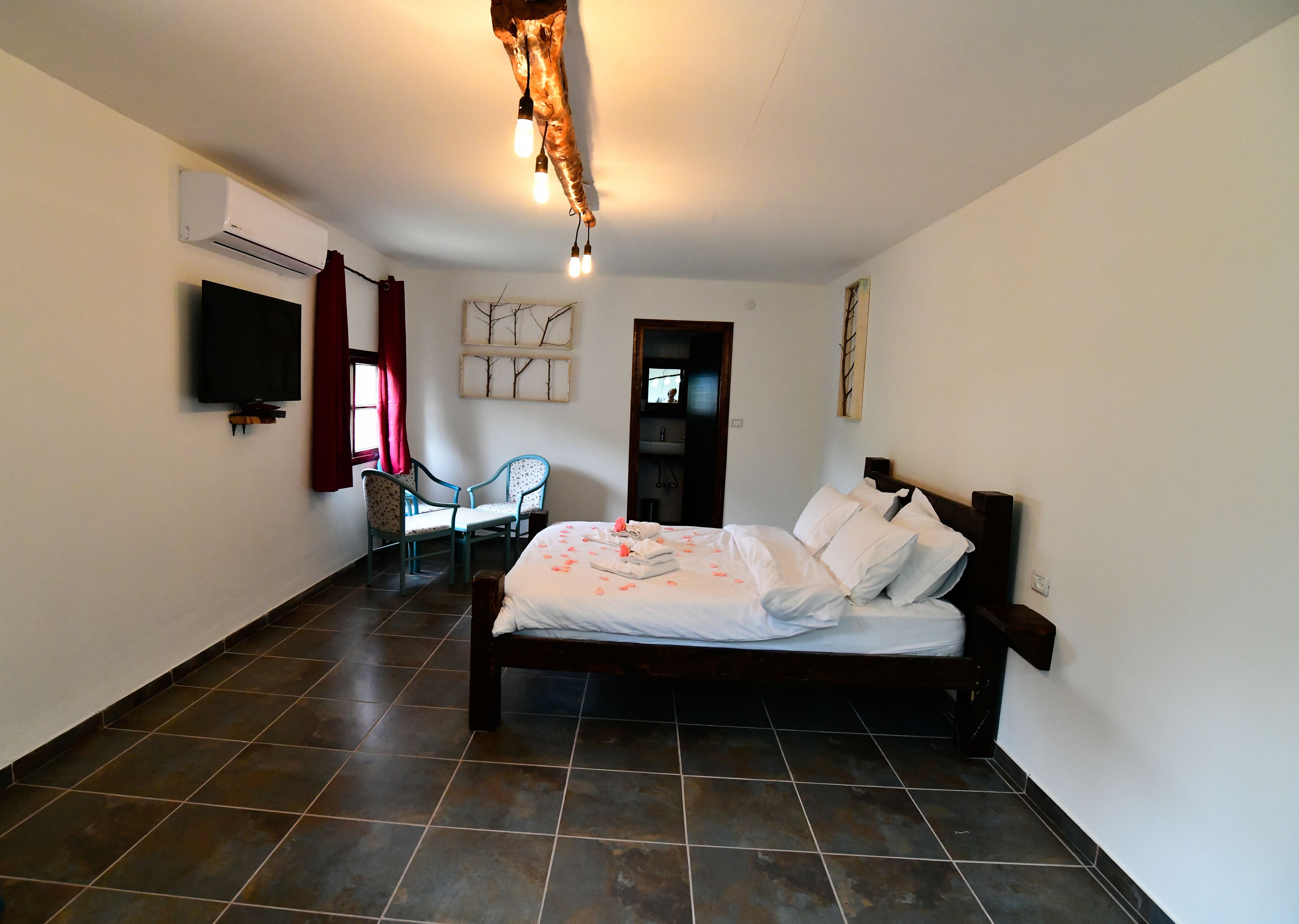 Een slaapkamer met een bed, twee stoelen, een televisie en een airconditioner.
