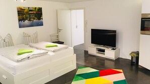 Un dormitorio moderno con cama, televisor y una alfombra de diseño geométrico.