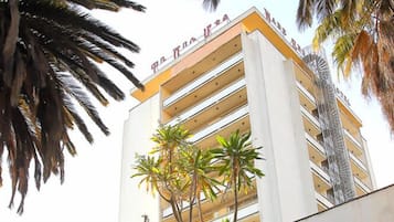 A multi-story hotel with balconies and palm trees.