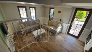 A spacious living area with a wooden floor, a white staircase, and a seating area with a sofa and armchairs. - Dalyan Villa Kiydan Apartments (Ortaca)
