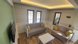 A living room with two sofas, a white coffee table, and a flat-screen TV. - Dalyan Villa Kiydan Apartments (Ortaca)