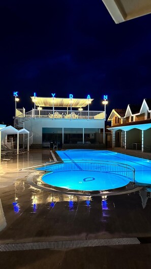A swimming pool with a covered deck area, a building with illuminated letters spelling 'KYDAN,' and a clear night sky. - Dalyan Villa Kiydan Apartments (Ortaca)
