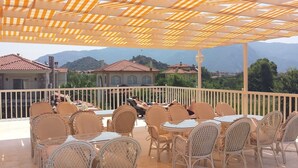 A terrace with wicker chairs and tables, overlooking a mountainous landscape. - Dalyan Villa Kiydan Apartments (Ortaca)