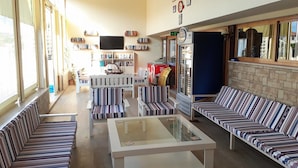 A spacious living room with striped sofas, a glass coffee table, and a bookshelf filled with books. - Dalyan Villa Kiydan Apartments (Ortaca)