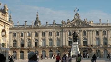 A grand historic building with a symmetrical facade, large windows, and statues.