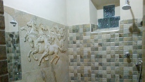 Un baño con pared de mosaicos, inodoro blanco, lavamanos y ducha.