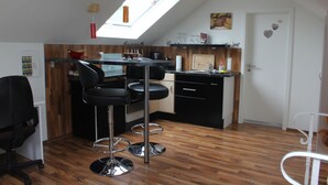 A modern kitchen with a skylight, wooden flooring, and a bar area with stools. - Ferienwohnung Bergisch Land (Wermelskirchen)