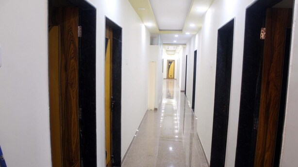 Un pasillo largo y estrecho con puertas a ambos lados, que da acceso a habitaciones. El suelo es brillante y reflectante.