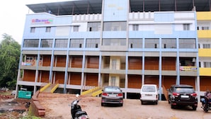 Un edificio de varios pisos con un letrero que indica que es un hotel. Hay varios vehículos estacionados adelante, incluyendo un coche y una camioneta.