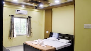 Habitación de hotel con cama, aire acondicionado, ventilador de techo y ventana con cortinas.