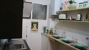 A compact kitchen with a sink, stove, and a small countertop with plates and cups. - Mila Guest House (Rome)