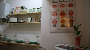 A kitchen with shelves holding various items like jars and a poster of Andy Warhol's artwork. - Mila Guest House (Rome)
