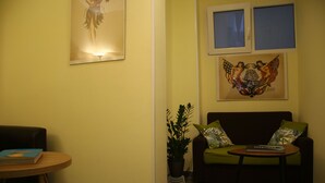A living room with a sofa, a small table, a potted plant, and artwork on the walls. - Mila Guest House (Rome)