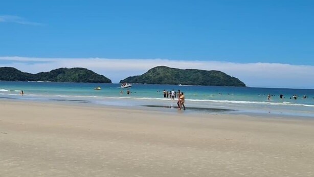 A beach with clear skies, calm waters, and distant green hills. - VELINN Pousada Recanto dos Tangaras (São Sebastião)