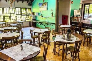 A restaurant with multiple tables and chairs, a staircase, and a view of the outdoors. - VELINN Pousada Recanto dos Tangaras (São Sebastião)