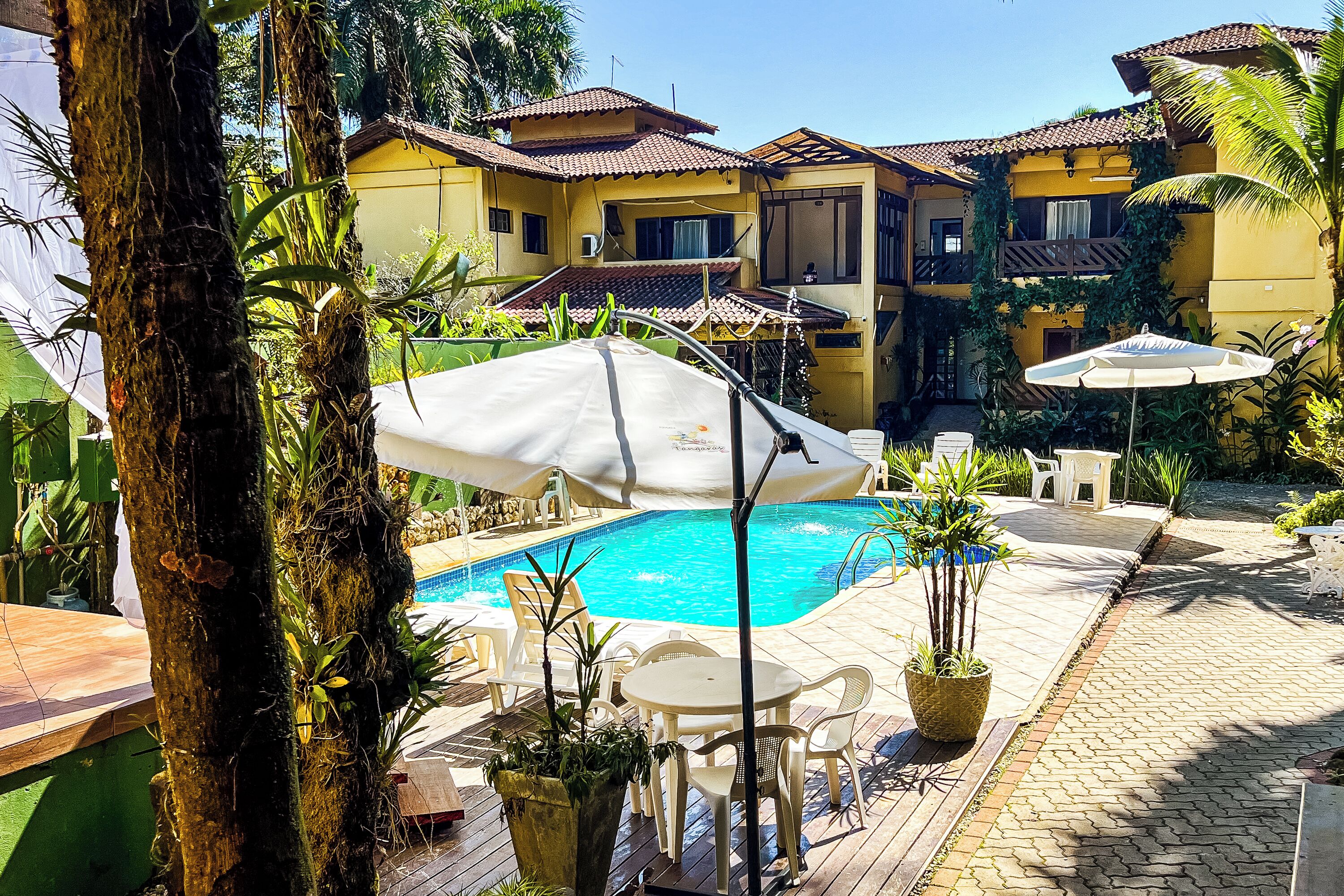 A pool area with a tiled deck, lounge chairs, and umbrellas.