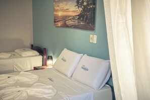 Une chambre d’hôtel avec deux lits, un tableau représentant un coucher de soleil et une table de chevet avec une lampe.