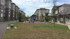 Un terrain de jeux avec des balançoires et un toboggan, entouré d’immeubles d’habitation.