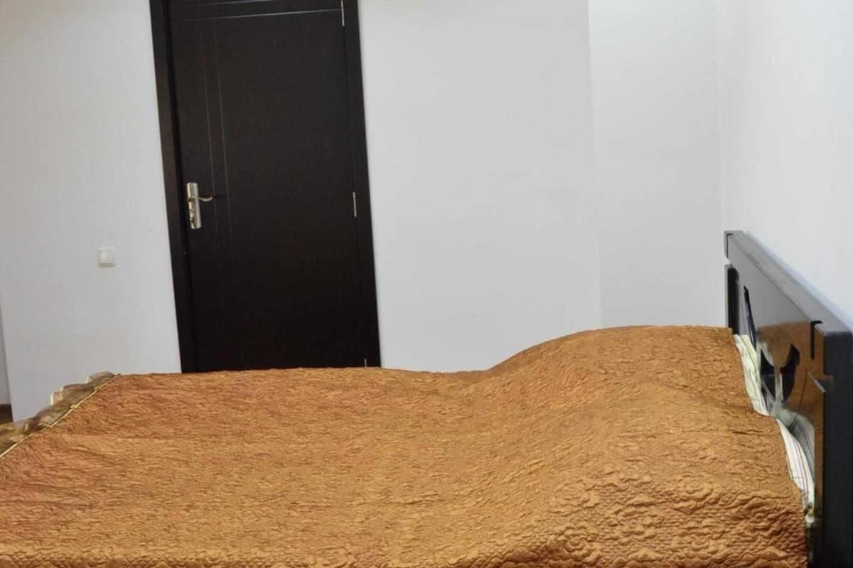 A room with a bed, a door, and a white wall.