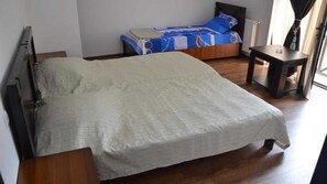 A bedroom with a bed, a bedside table, a small table, and a window with curtains. - Hotel Bagineti (Mtskheta)