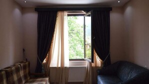 A room with a large window, a sofa, and a black armchair. - Hotel Bagineti (Mtskheta)