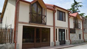 A two-story building with a balcony, large windows, and a sign indicating it is a hotel. - Hotel Bagineti (Mtskheta)