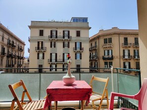 A balcony with a table and chairs, overlooking a river with buildings in the background. - Under40 - Students Apartment - Adults Only (Palermo)