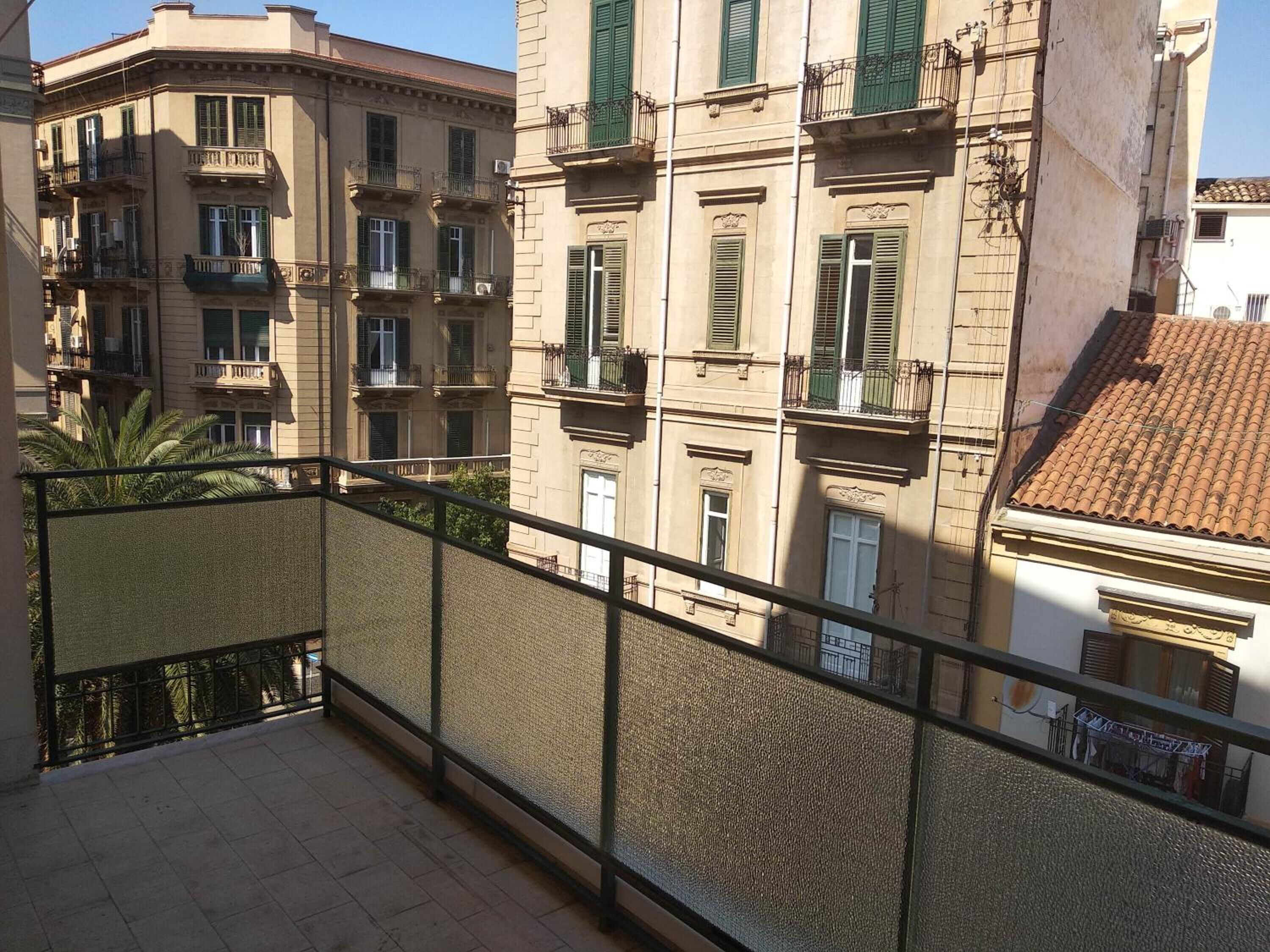 A balcony with a metal railing overlooking a building with multiple windows and balconies.