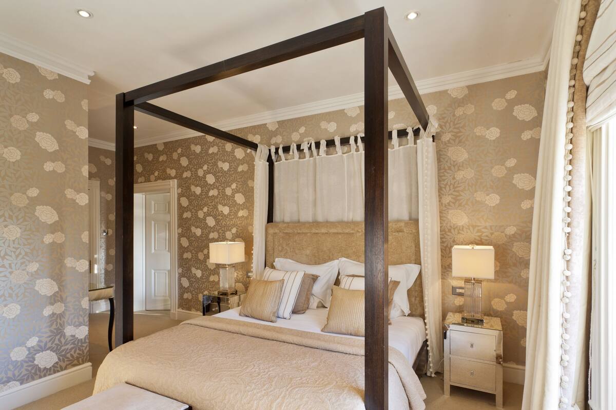 A four-poster canopy bed with a headboard, bedside tables, and lamps.