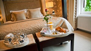 Un plateau de petit-déjeuner soigneusement préparé, avec des croissants, un verre de jus d’orange et une rose posée sur la table de chevet d’une chambre d’hôtel.