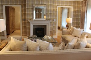 A living room with a fireplace, a sofa, a glass coffee table, and a lamp.