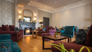 Un salon spacieux doté d’une cheminée, de sièges confortables et d’un grand miroir.