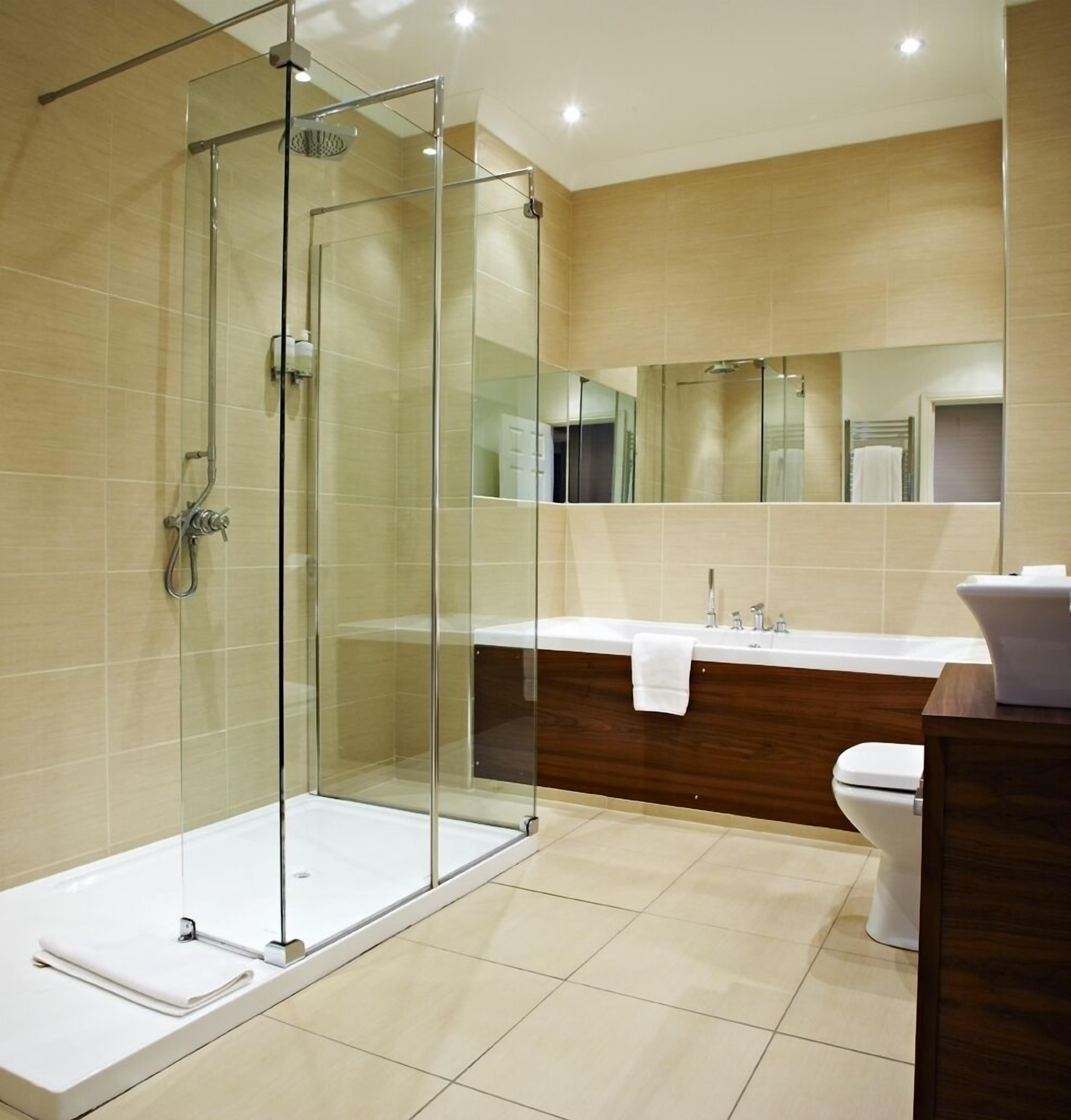 A modern bathroom with a glass-enclosed shower, a wooden vanity, and a large mirror.