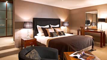 Habitación de hotel con una cama grande, mesitas de noche, un escritorio, una silla y un espejo.