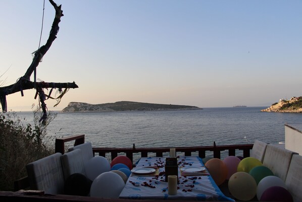 Una mesa lista para comer con vista al mar y un barco a lo lejos.