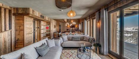 A spacious living area with a large sectional sofa, a coffee table, and a view of a snowy landscape through large windows.
